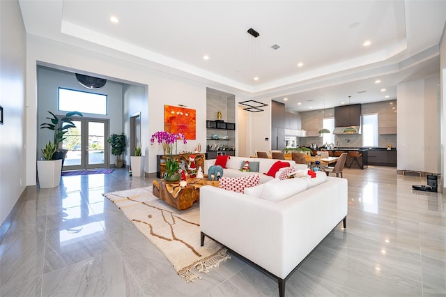 living room featuring french doors and a tray ceiling