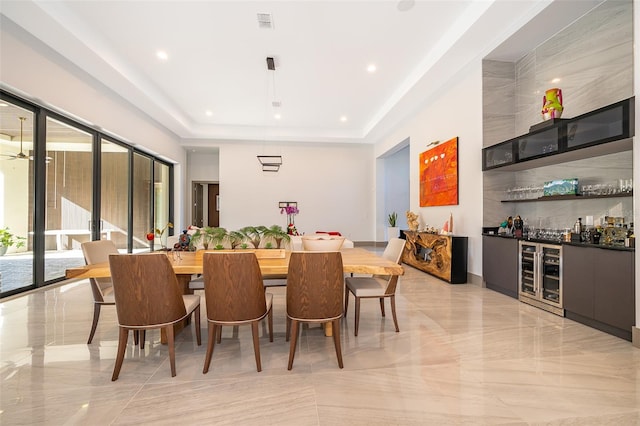 dining space with bar area, wine cooler, and a tray ceiling