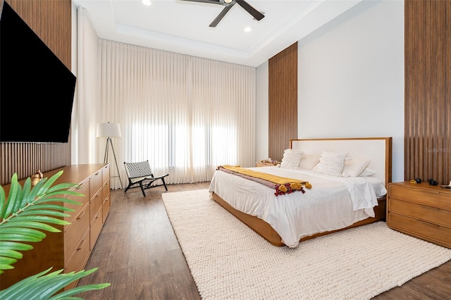 bedroom with a tray ceiling, ceiling fan, and dark hardwood / wood-style flooring