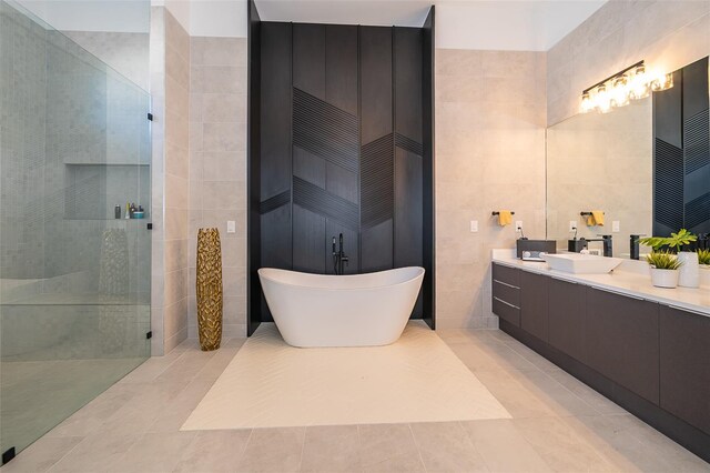 bathroom featuring shower with separate bathtub, vanity, tile patterned floors, and tile walls