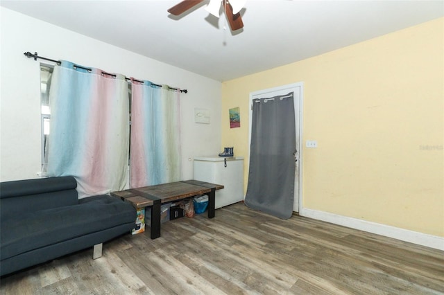 sitting room with ceiling fan and wood-type flooring