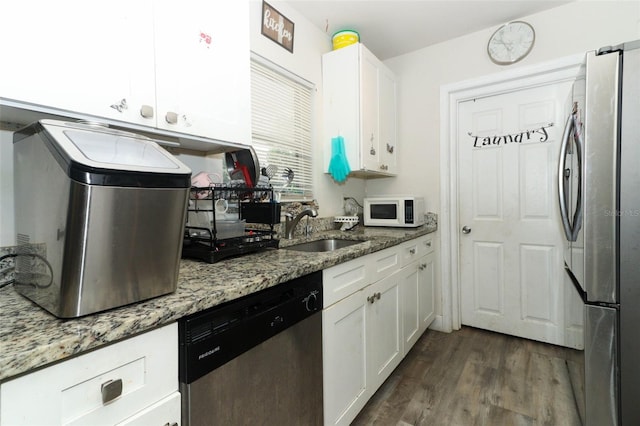 kitchen with light stone countertops, appliances with stainless steel finishes, dark wood-type flooring, sink, and white cabinetry