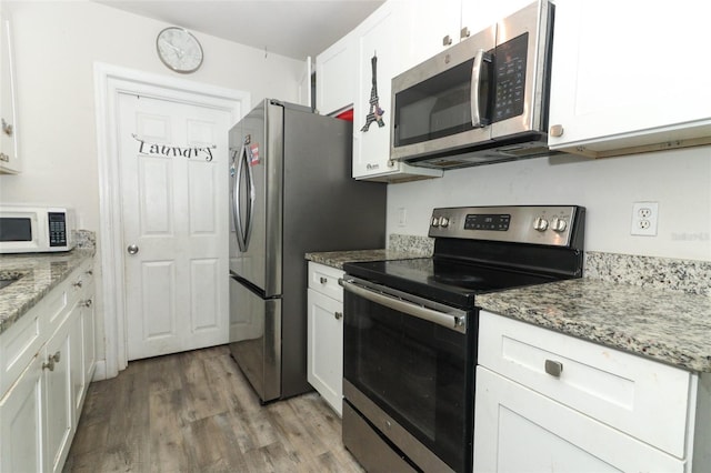 kitchen featuring hardwood / wood-style floors, light stone countertops, white cabinetry, and stainless steel appliances