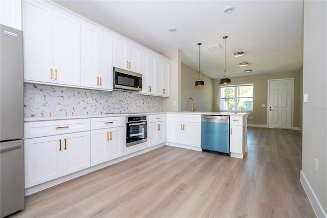 kitchen featuring decorative light fixtures, white cabinetry, kitchen peninsula, and stainless steel appliances