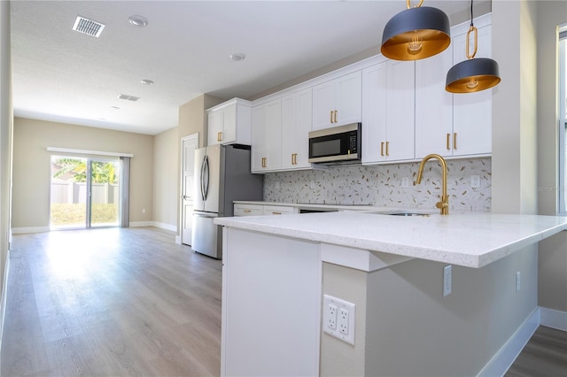 kitchen with white cabinets, sink, decorative backsplash, appliances with stainless steel finishes, and decorative light fixtures