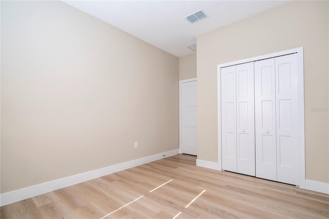 unfurnished bedroom featuring a textured ceiling, light hardwood / wood-style floors, and a closet