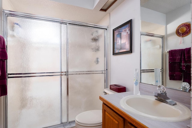 bathroom with vanity, a shower with shower door, a textured ceiling, and toilet