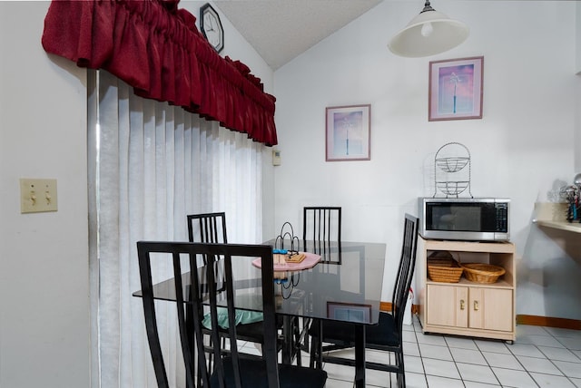 dining area featuring lofted ceiling, a textured ceiling, and light tile patterned floors