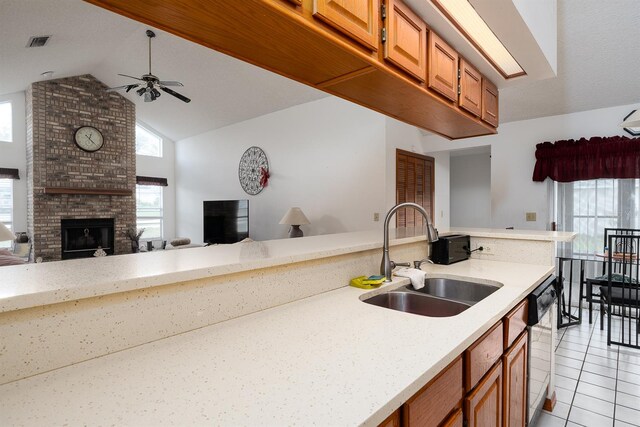 kitchen with vaulted ceiling, ceiling fan, sink, light tile patterned floors, and a fireplace