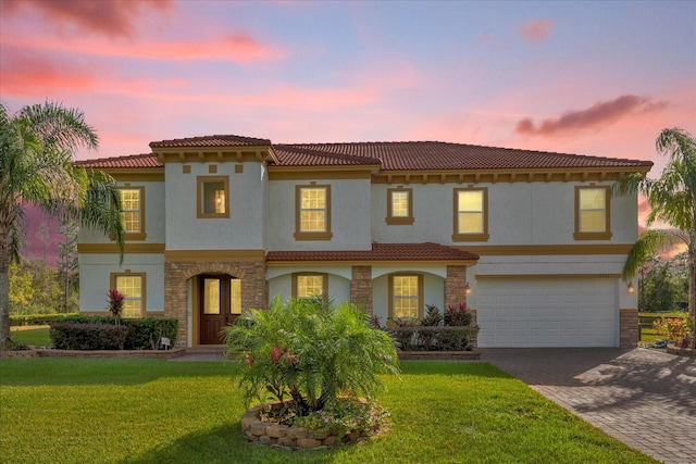 mediterranean / spanish-style house featuring a lawn and a garage