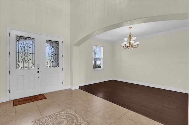 entryway with light hardwood / wood-style floors, an inviting chandelier, and ornamental molding