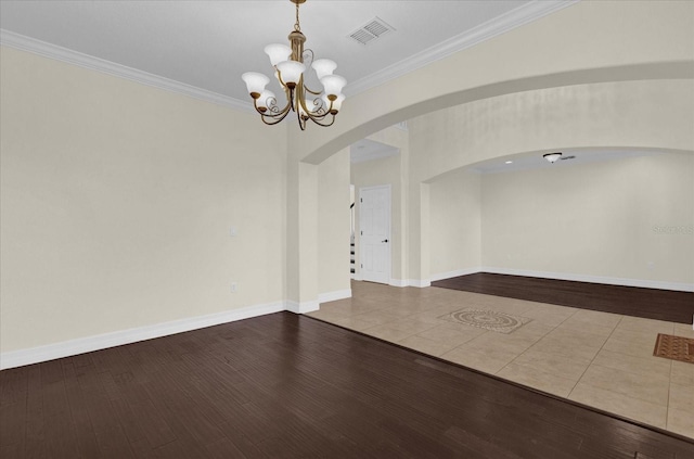 spare room with hardwood / wood-style floors, ornamental molding, and a chandelier