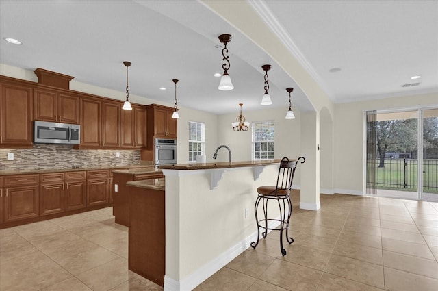 kitchen with pendant lighting, a center island with sink, stainless steel appliances, and plenty of natural light