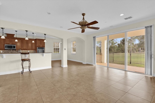 unfurnished living room with ceiling fan, light tile patterned floors, and crown molding