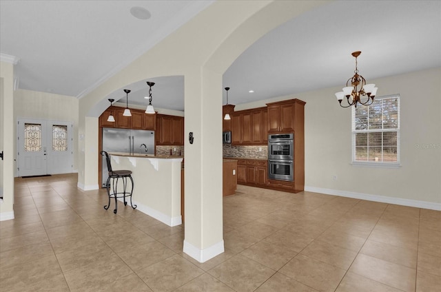 kitchen featuring a chandelier, a breakfast bar, stainless steel appliances, and hanging light fixtures