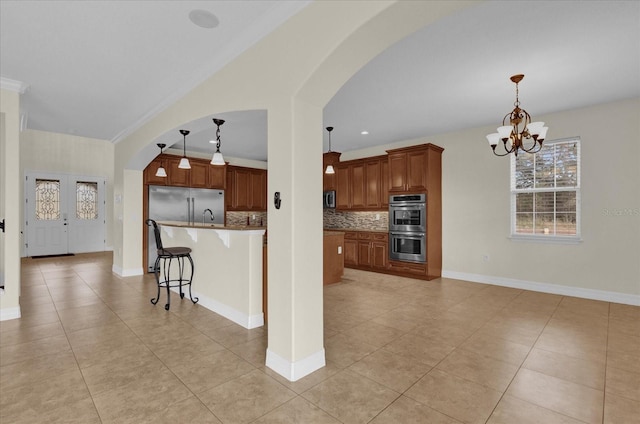 19206 Robertson St, Orlando, FL 32833 - kitchen featuring stainless steel appliances, arched walkways, light tile patterned floors, a kitchen breakfast bar, and a chandelier