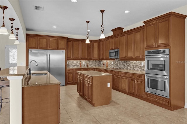 kitchen featuring appliances with stainless steel finishes, sink, pendant lighting, an island with sink, and light tile patterned flooring