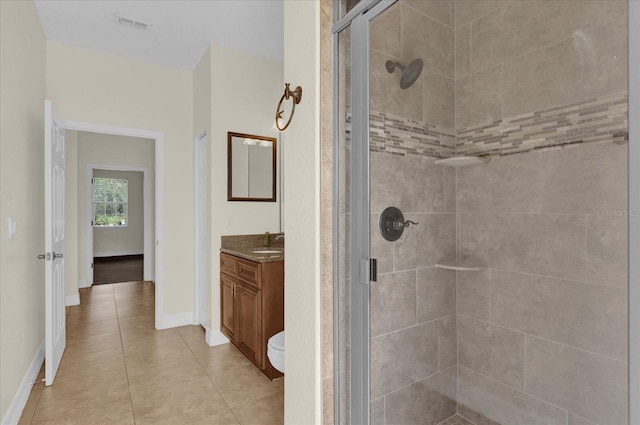 bathroom with tile patterned flooring, vanity, a shower with shower door, and toilet