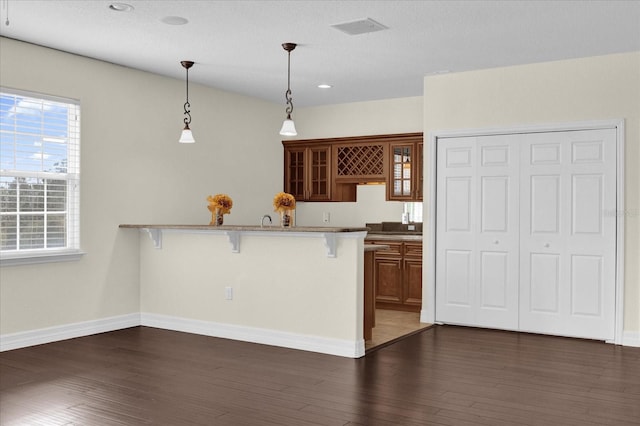 19206 Robertson St, Orlando, FL 32833 - kitchen with a breakfast bar, glass insert cabinets, a peninsula, decorative light fixtures, and brown cabinets