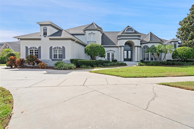 french provincial home with a front lawn and french doors