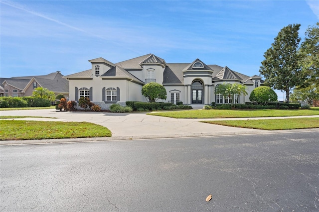 french country inspired facade with a front lawn and french doors