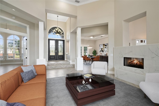 interior space with parquet floors, an inviting chandelier, french doors, crown molding, and a towering ceiling