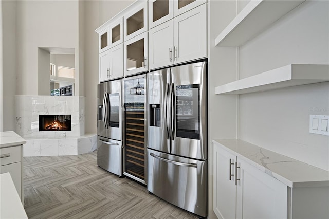 kitchen featuring light stone countertops, stainless steel fridge, white cabinetry, and a tile fireplace