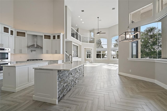 kitchen with plenty of natural light, an island with sink, and a high ceiling