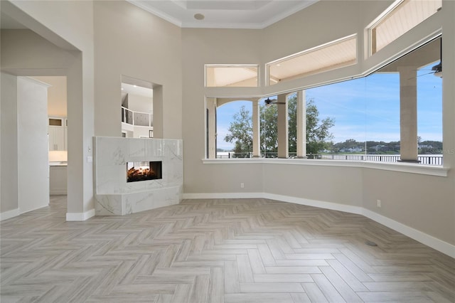 unfurnished living room featuring a multi sided fireplace, crown molding, a high ceiling, and light parquet floors