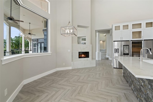 unfurnished living room with a high ceiling, light parquet floors, ceiling fan, and sink