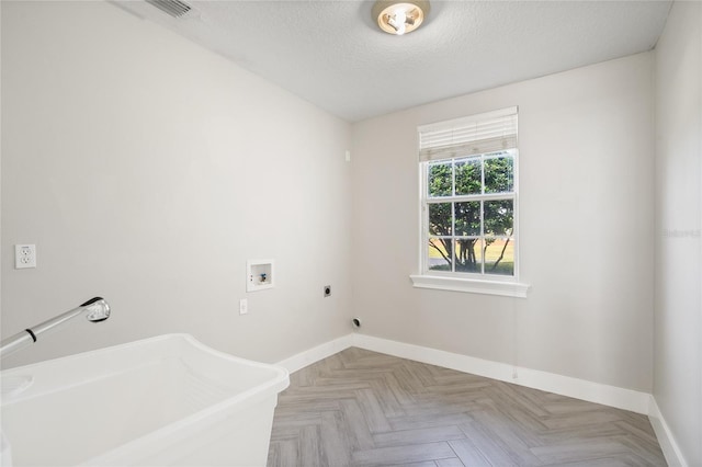 clothes washing area featuring hookup for an electric dryer, washer hookup, a textured ceiling, and light parquet flooring