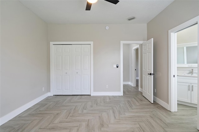 unfurnished bedroom featuring ceiling fan, a closet, connected bathroom, and light parquet floors