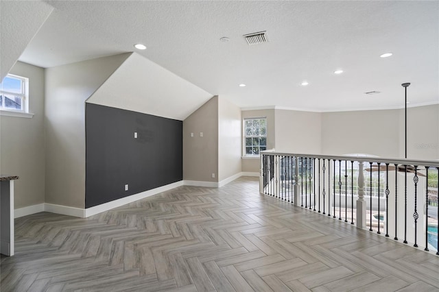 additional living space featuring a textured ceiling, light parquet flooring, and a wealth of natural light