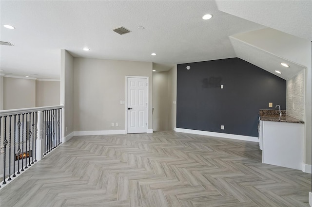 spare room featuring a textured ceiling, light parquet flooring, and vaulted ceiling