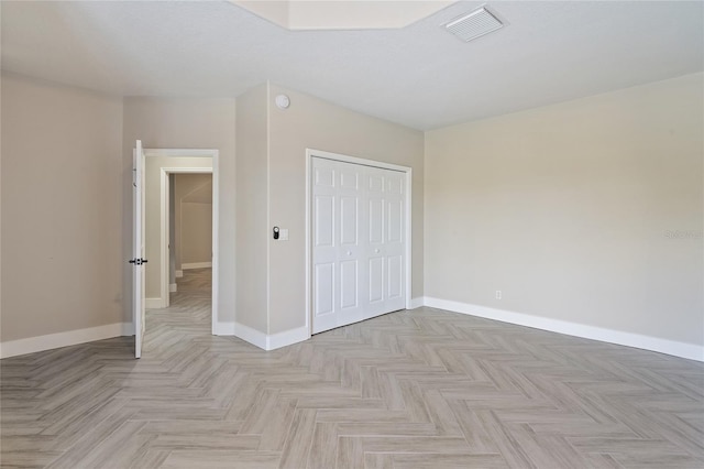 unfurnished bedroom featuring light parquet flooring and a closet