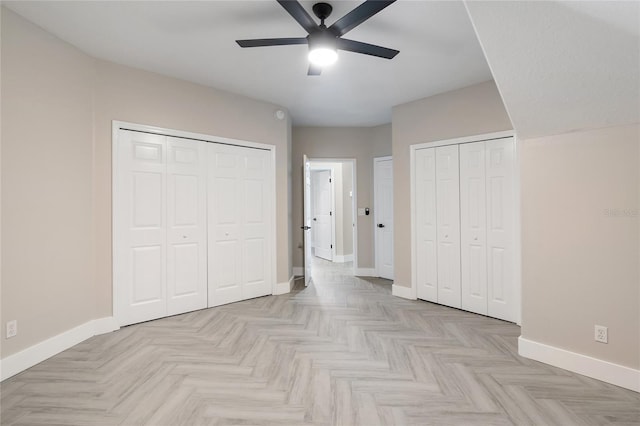 unfurnished bedroom featuring light parquet flooring, two closets, and ceiling fan