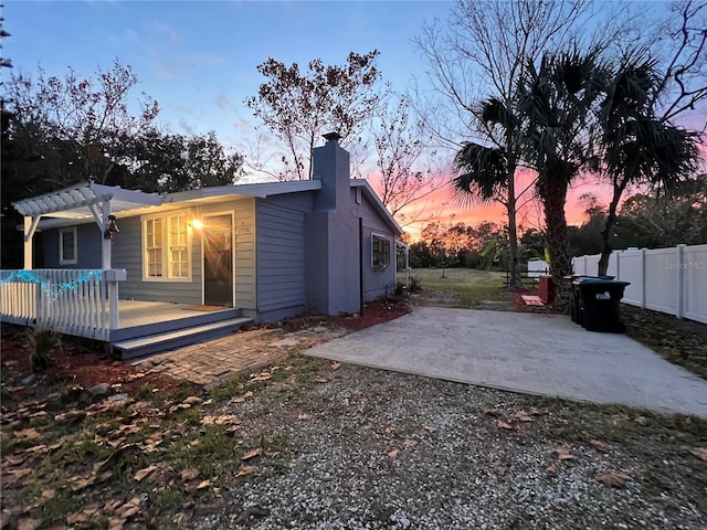 back house at dusk featuring a patio area, a deck, and a pergola