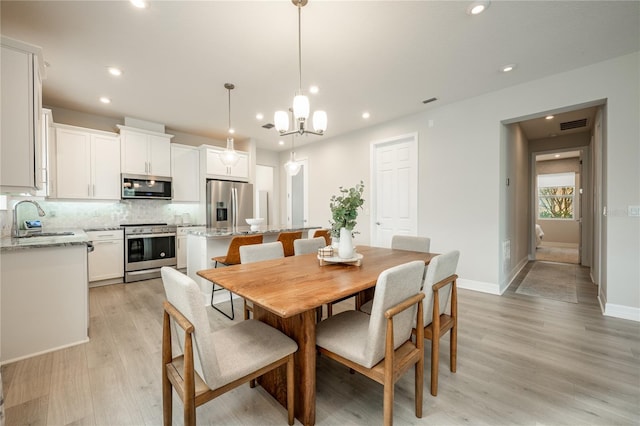 dining room featuring a chandelier, light wood-type flooring, and sink