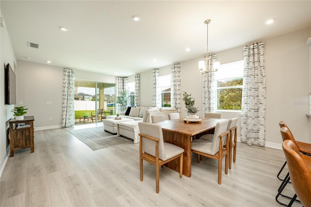 dining room featuring plenty of natural light, an inviting chandelier, and light hardwood / wood-style flooring