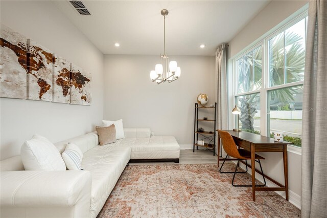 living room featuring an inviting chandelier, a wealth of natural light, and light hardwood / wood-style flooring