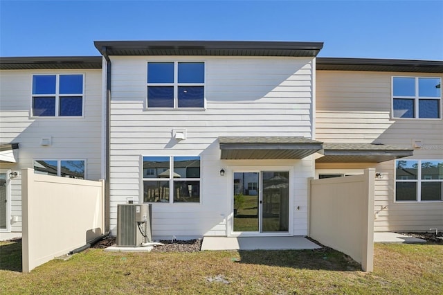 rear view of property with central AC unit and a lawn