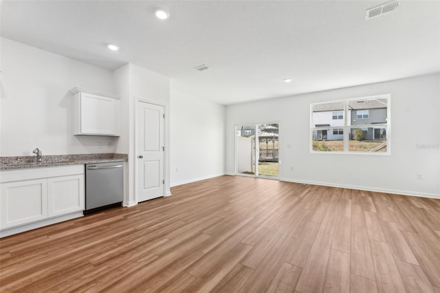 kitchen featuring white cabinetry, stainless steel dishwasher, sink, and light wood-type flooring