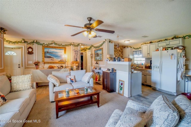 carpeted living room with a textured ceiling and ceiling fan