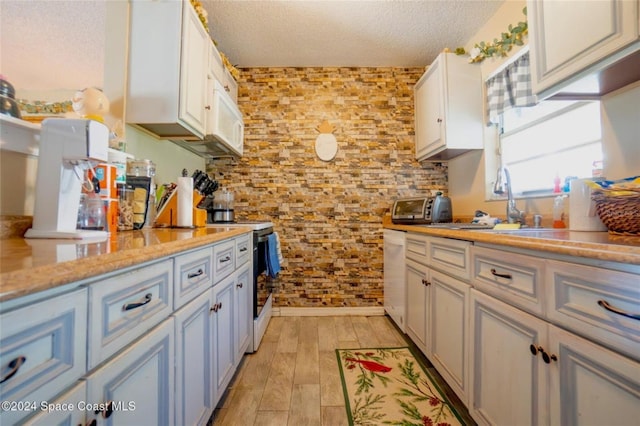 kitchen with stainless steel electric stove, sink, a textured ceiling, light hardwood / wood-style floors, and white cabinetry