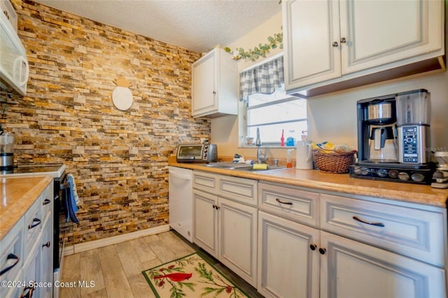 kitchen with a textured ceiling, white appliances, sink, light hardwood / wood-style flooring, and white cabinets