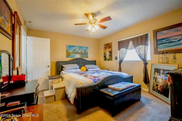 carpeted bedroom featuring ceiling fan and a textured ceiling