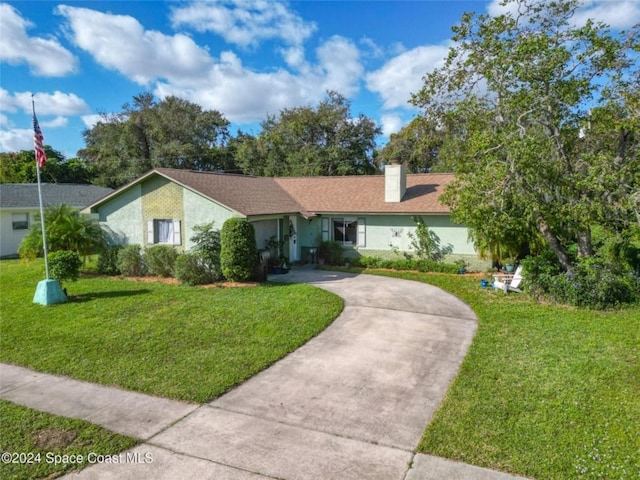 ranch-style home with concrete driveway, a front lawn, a chimney, and stucco siding