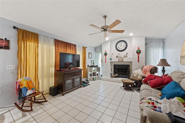 living room with a brick fireplace, a textured ceiling, ceiling fan, light tile patterned floors, and lofted ceiling