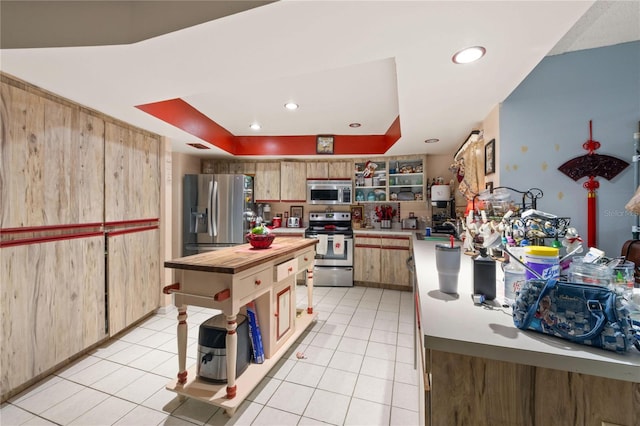 kitchen featuring appliances with stainless steel finishes, a center island, light tile patterned floors, and light brown cabinetry