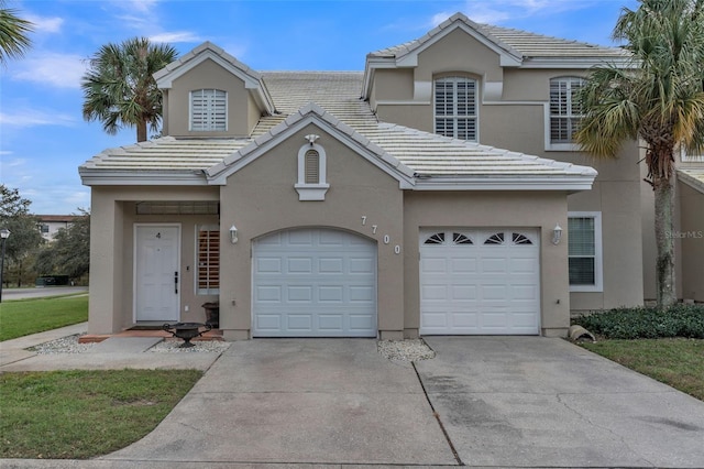 view of front of property with stucco siding, a garage, driveway, and a tiled roof